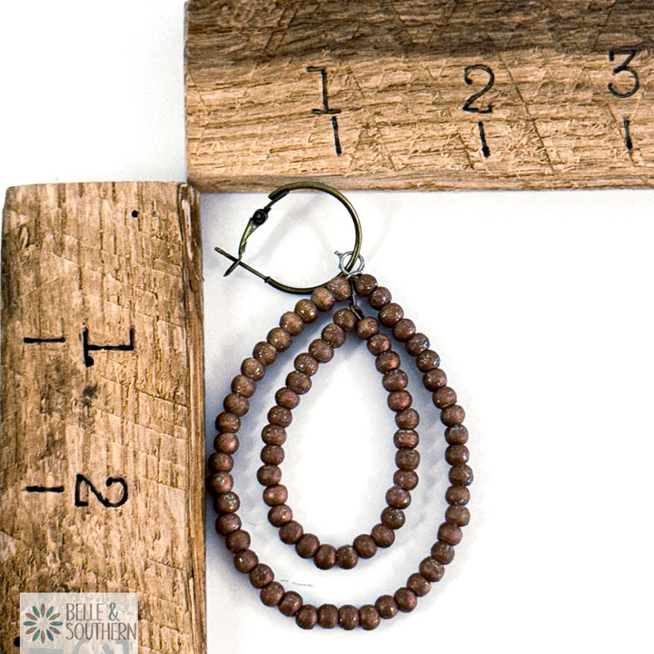 Light Brown beaded earrings on a white surface with a wooden ruler for scale.