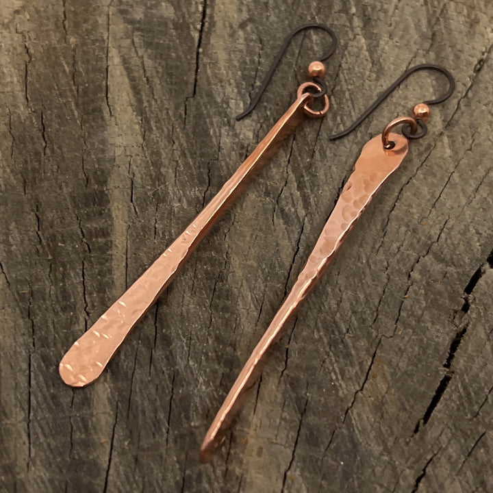 Copper bar earrings on barn wood